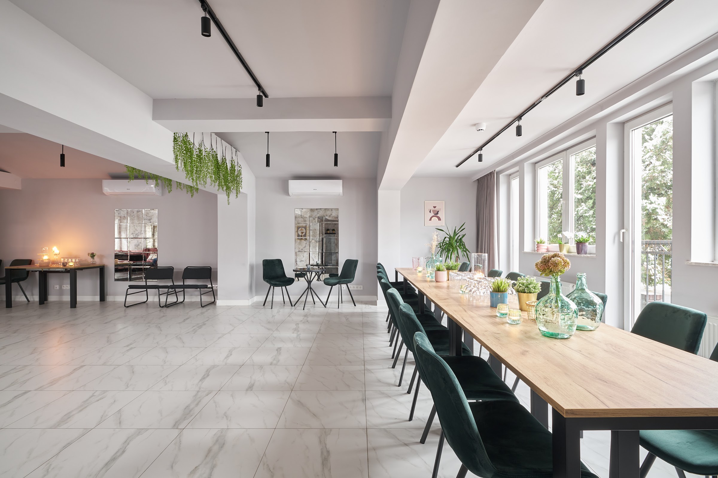 Jasna sala główna Bielska 30 Event Space z długim drewnianym stołem i zielonymi krzesłami